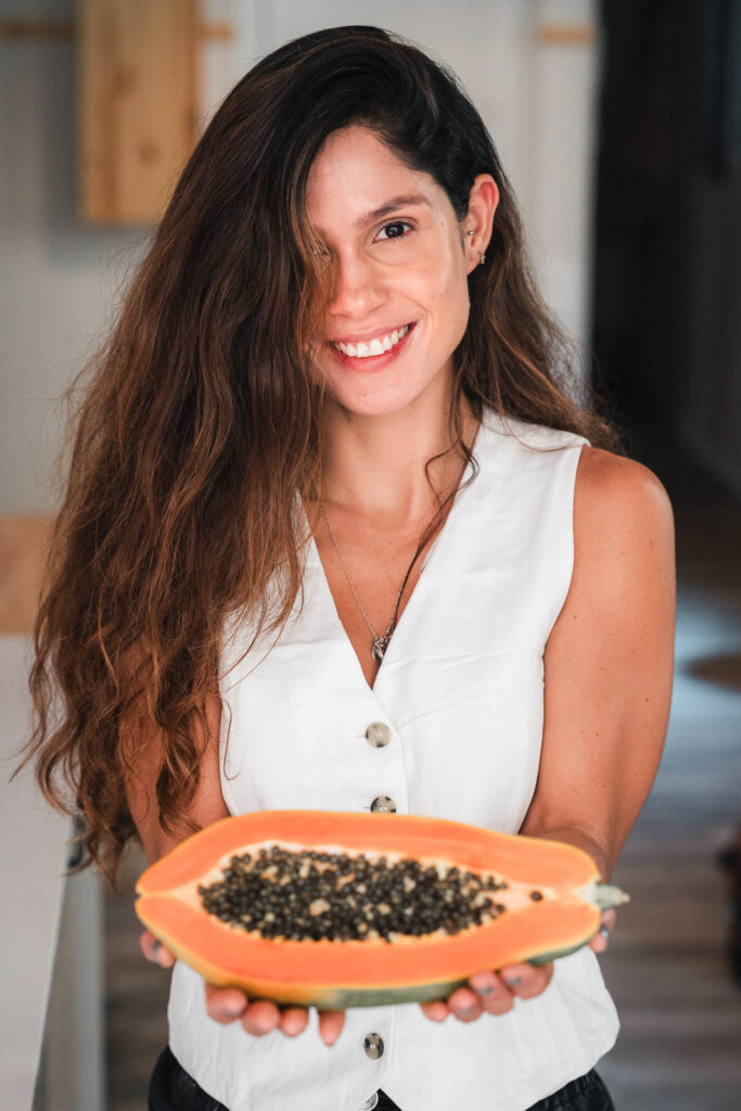 Nella de HolisticVibz mostrando una papaya en las manos que representa la nutrición holística