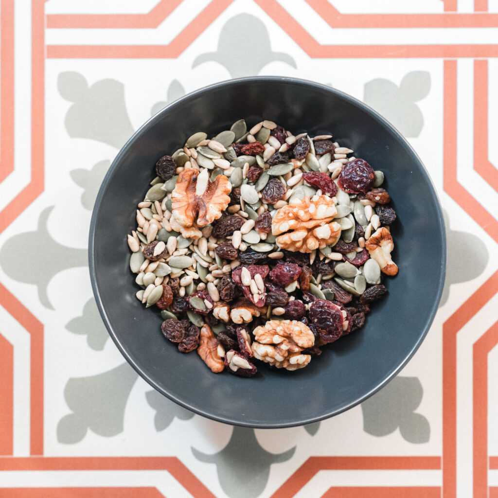 Bowl de frutos secos sobre un fondo de cerámica en mosaicos representando la nutrición holística y los ácidos grasos esenciales DHA, EPA para la óptima nutrición para un cabello saludable